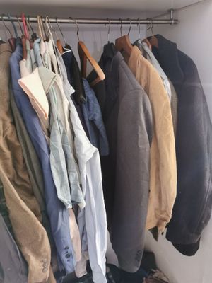 a lot of clothes hanging on a rack in a closet