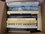 many books in a box that are stacked on top of each other