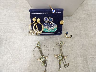 Deux paires de boucles d'oreilles et un sac à main sont posés sur une table.