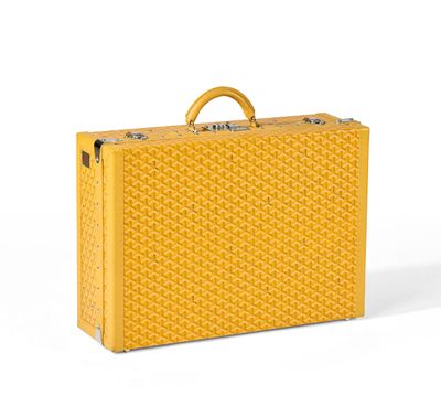 La valise jaune est posée sur une surface blanche.