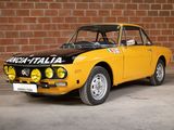 an old yellow car parked in front of a brick wall