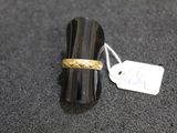 a ring with a gold band sitting on top of a black surface