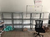 a black office chair sitting in front of a metal shelving