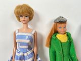 two dolls standing next to each other on a white surface