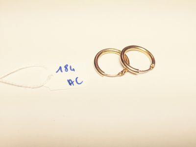 two gold rings on a white surface with a price tag