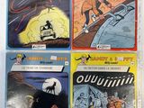 quatre bandes dessinées posées sur une table avec un fond blanc