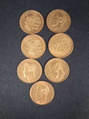 six pièces d'or sont disposées en triangle sur une surface noire