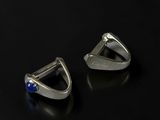 a pair of silver earrings with blue stones on a black surface