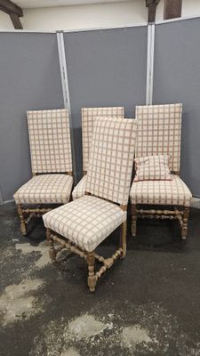 quatre chaises et un repose-pieds dans une pièce, avec un mur derrière elles
