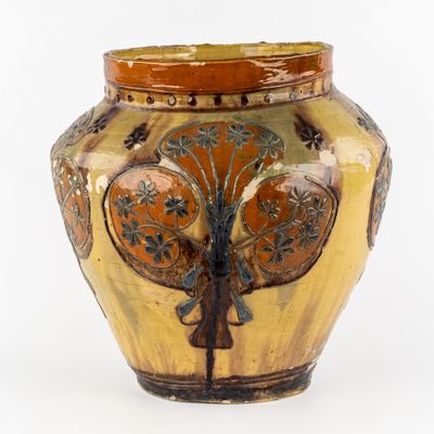 un vase jaune orné d'un arbre sur fond blanc
