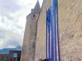 a tall blue sculpture in front of a stone building