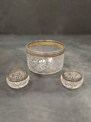 un saladier en argent et en verre et deux petits bols posés sur une table