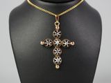 un collier noir et doré orné d'une croix, posé sur un mannequin