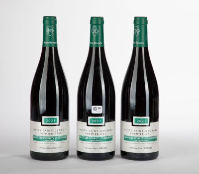 trois bouteilles de vin rouge sont posées côte à côte sur une surface blanche