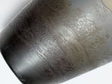 a close up of a black vase on a white surface