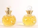 two bottles of perfume sitting on top of each other on a white surface