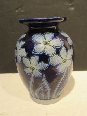 un vase bleu orné de fleurs blanches, posé sur une table