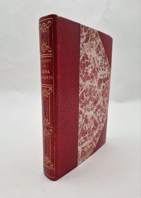 an old book with a red cover sitting on top of a white table