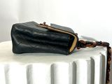 a black purse sitting on top of a white pedestal