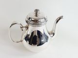a silver tea pot with a lid on a white table