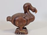 une image représentant une statue de canard en bois posée sur une surface blanche