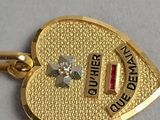 a gold heart shaped charm with a diamond on it