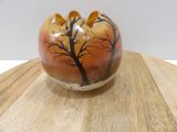 a vase with a tree on it sitting on a wooden table