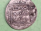 an old silver coin sitting on top of a green surface