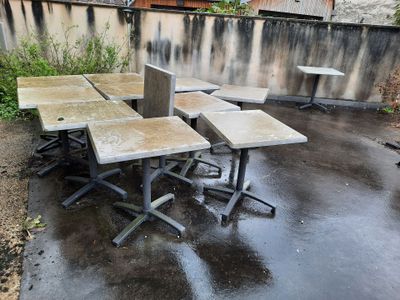 trois tables et deux chaises sur la terrasse en béton