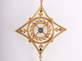 a close up of a gold pendant with a blue stone in the center