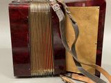 a red accordion sitting on a table with a strap around it