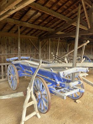un chariot bleu garé à l'intérieur d'une grange aux murs en bois