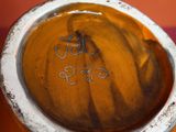 un vase orange bordé de blanc, posé sur une surface rose