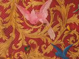 two birds that are flying in the air next to a red wall