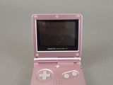 a small pink nintendo game console sitting on a table