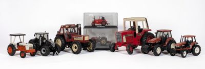 Plusieurs tracteurs miniatures sont alignés les uns à côté des autres sur une surface blanche