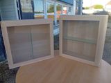 deux armoires en bois avec des étagères en verre, posées sur une table