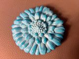 a blue flower brooch sitting on a brown surface