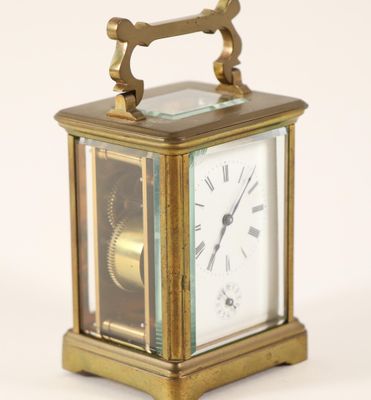 a small brass clock with roman numerals on the face