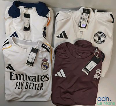 Trois maillots de football sont posés sur une table, encore étiquetés.