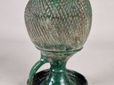 a green vase sitting on a stand on a white surface