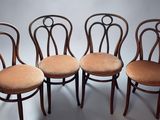four chairs with curved backs are lined up against a white background