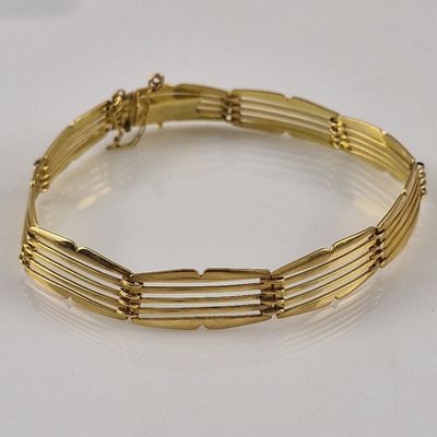 gold plated bracelet with five rows of links on a white surface