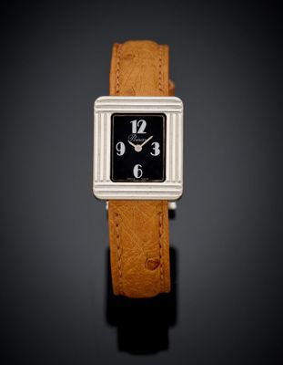une photo d'une montre carrée en noir et blanc montée sur un bracelet en cuir marron