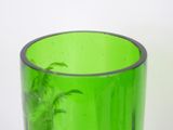 a green glass vase with a plant inside of it