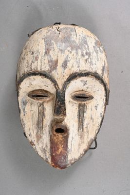 an old wooden mask hanging on a wall