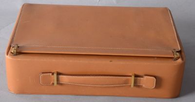 tan leather suitcase sitting on top of a white table