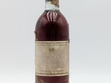 une vieille bouteille de vin posée sur une surface blanche