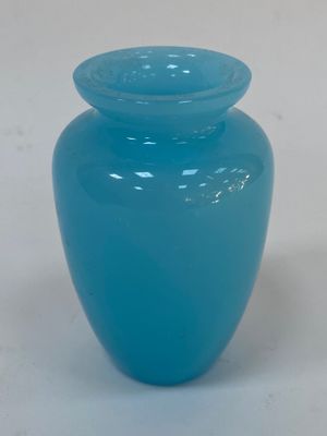 un vase bleu muni d'un couvercle, posé sur une surface blanche