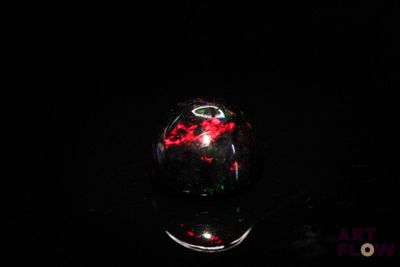 une image représentant une boule en verre rouge et noire posée sur une surface noire
